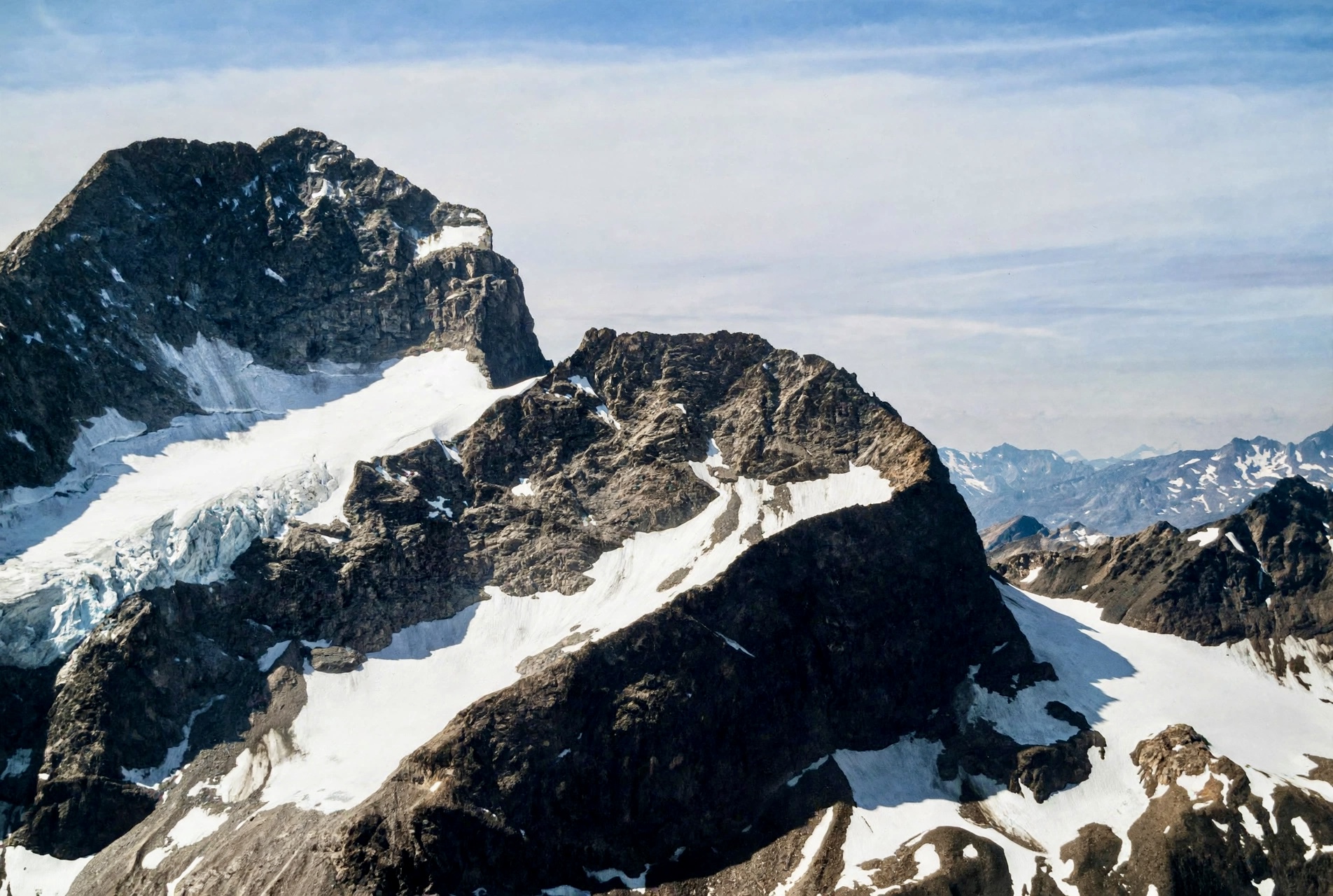 Felsgrat mit Restgletscher und Blick zu fernen Bergketten