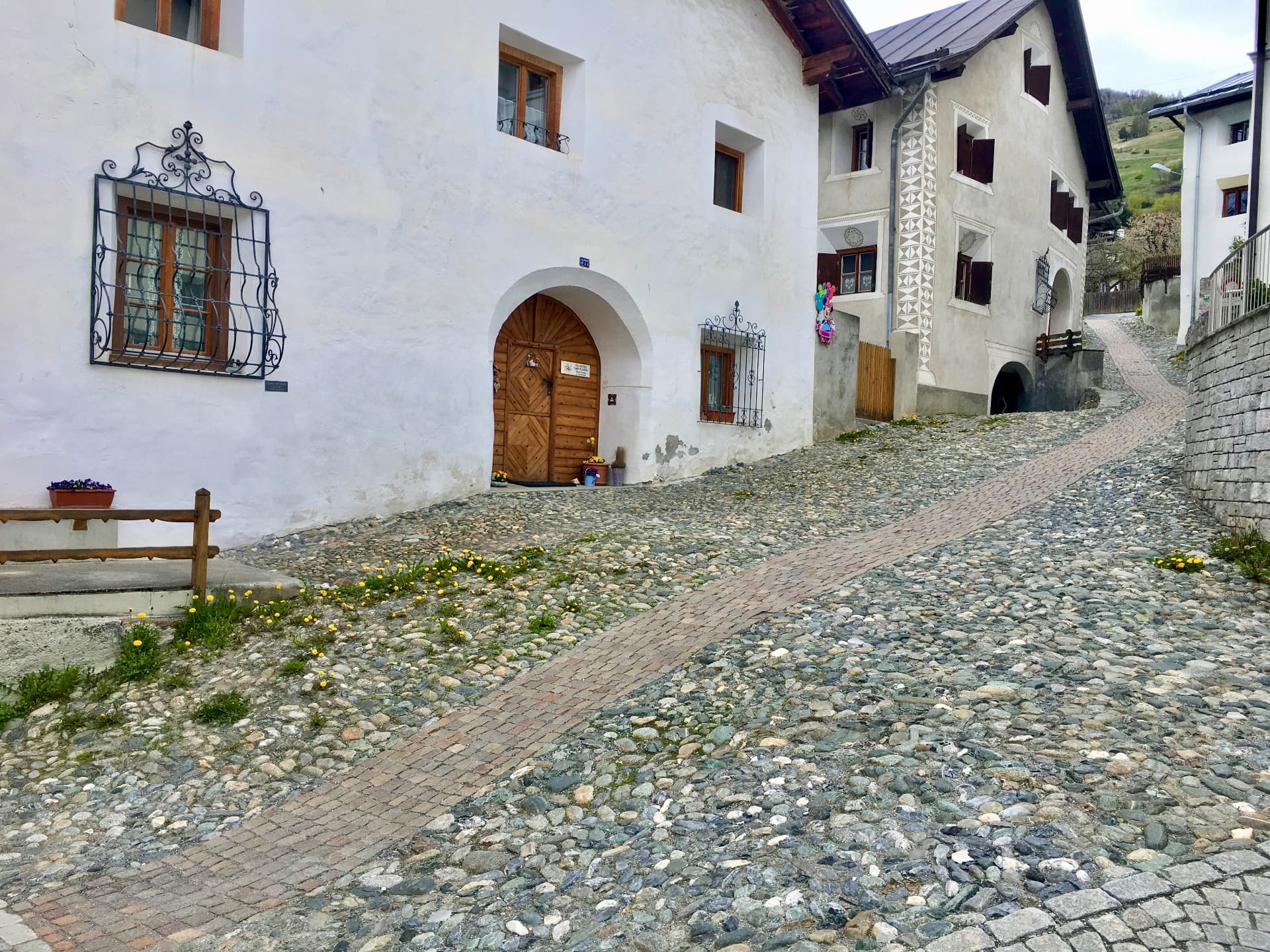 Steiler Pflasterweg entlang alter Engadinerhäuser