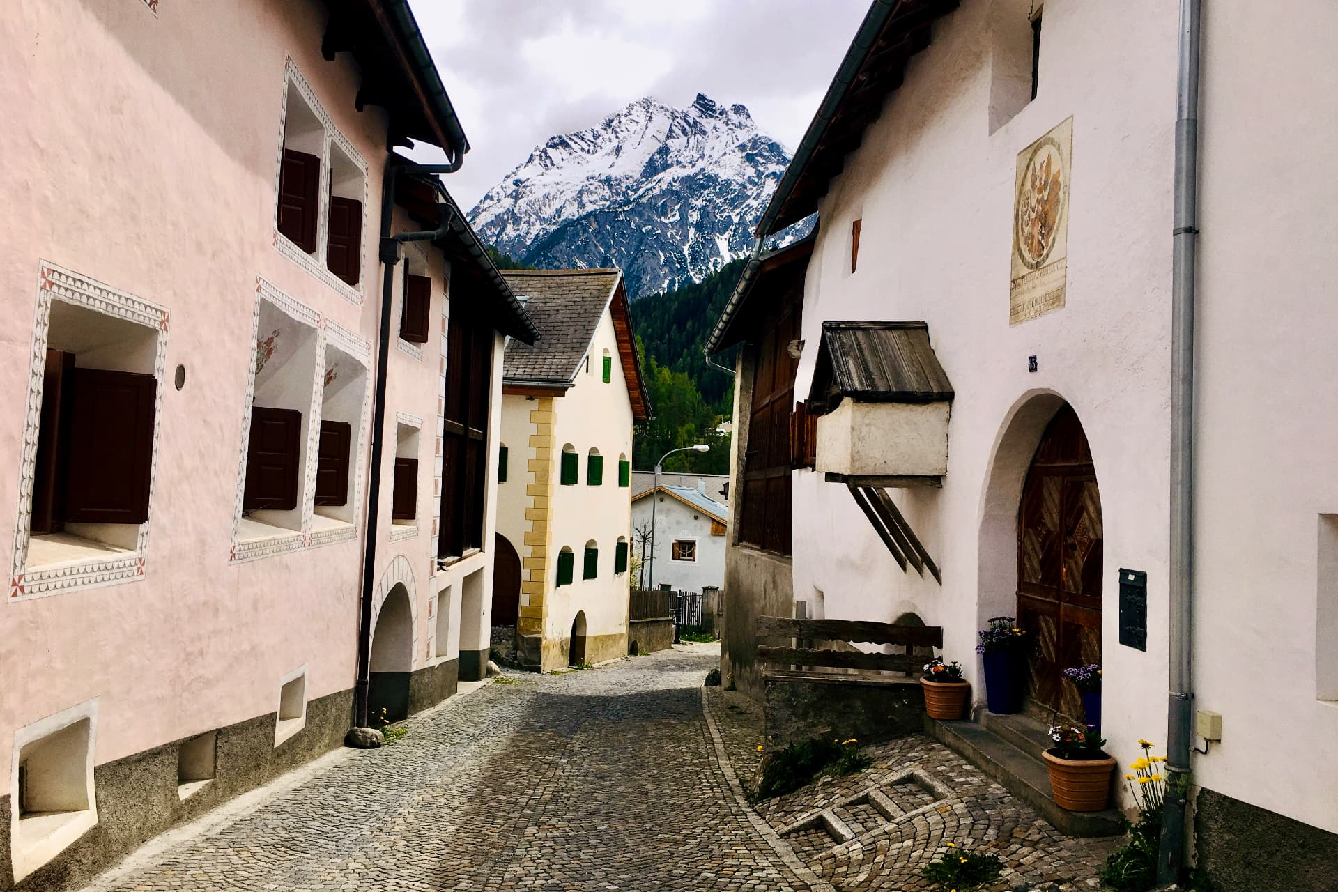 Gasse zwischen Engadiner Häusern mit Blick auf die Berge