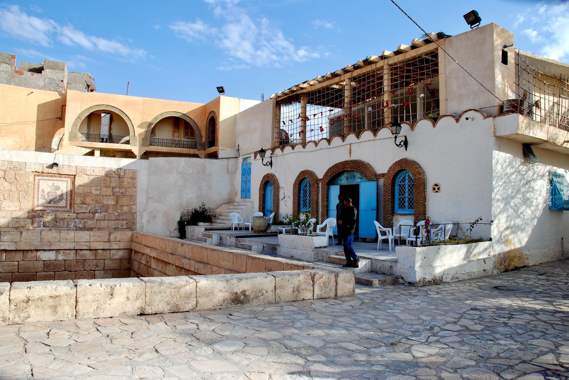 Sonniger Innenhof mit blauen Türen und gerahmtem Mosaik