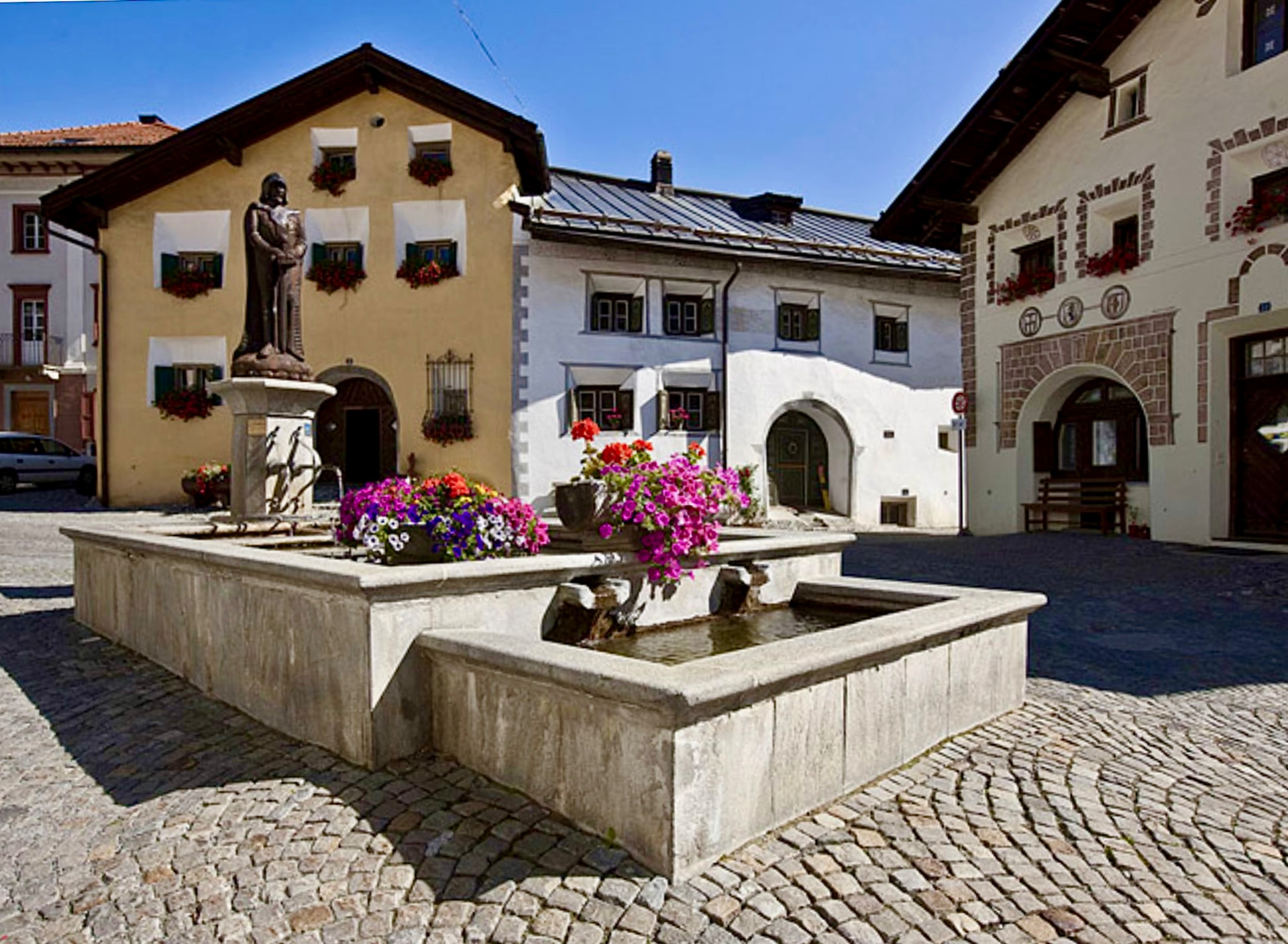 Blumengeschmückter Dorfbrunnen im Sommer