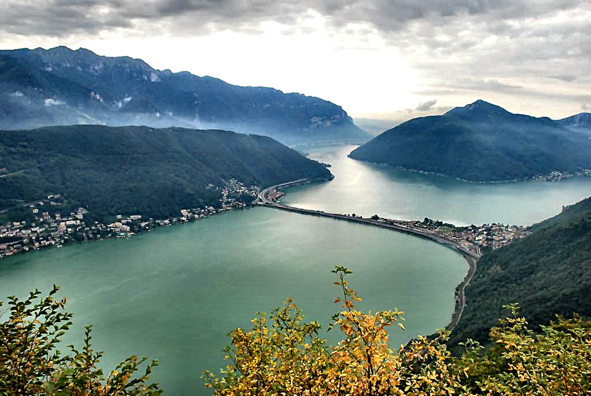 Panorama über den Luganersee mit dem Damm von Melide